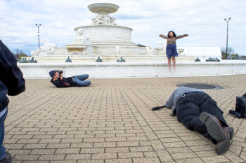 girl jumping by fountain as Rob Woodcox takes photos