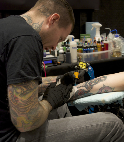 tattoo artist adds tattoo to client's skin