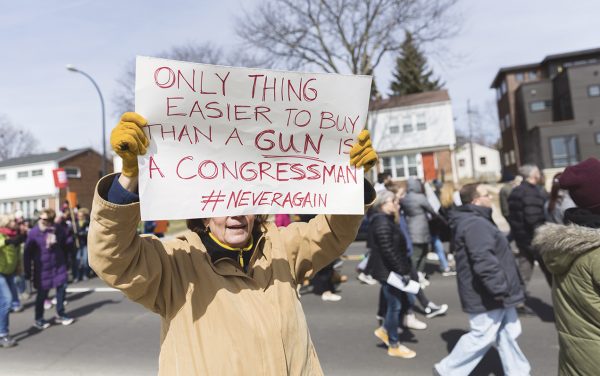 An attendee at the “March For Our Lives” event holding a sign with a statement to Congress that reads “Only thing easier to buy than a gun is a Congressman #NEVERAGAIN.”