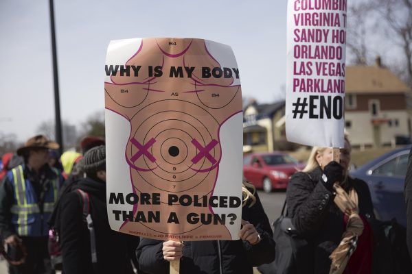 A sign that reads “Why is my body more policed than a gun?”