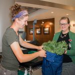 Anthea van Geloven of Green Things Farm puts produce in a bag for St. Joe employee Chloe Foreman