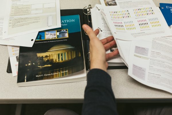 Frustrated student graples with unbound louse leaf “textbook”. Sara Faraj | Washtenaw Voice