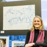 Edie Ostapik poses with her piece, “Surface Movement Blues.” She won first place for her work. Sara Faraj | Washtenaw Voice