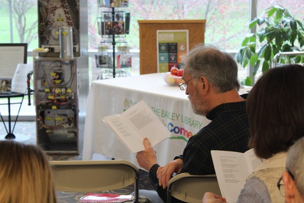 Poetry Club member Ron Pagereski reads along from the “Poetry Sustains” anthology while poets perform. Lilly Kujawski | Washtenaw Voice
