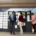 Librarians assist students in finding a human story they’d like to hear from the board display of all the stories featured in the Human Library. Lily Merritt | Washtenaw Voice