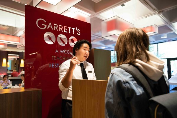 Kevin Yi, a culinary student, directs customers at the host stand as part of his dining room services class where students receive real experiences working in a restaurant while having the safety of instructors supervising their work. Lily Merritt | Washtenaw Voice