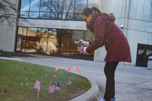 Jessica Ponce-Torres, technical assistant for Student Development, sets up flags outside of the Student Center in honor of Veterans Day. Lilly Kujawski | Washtenaw Community College