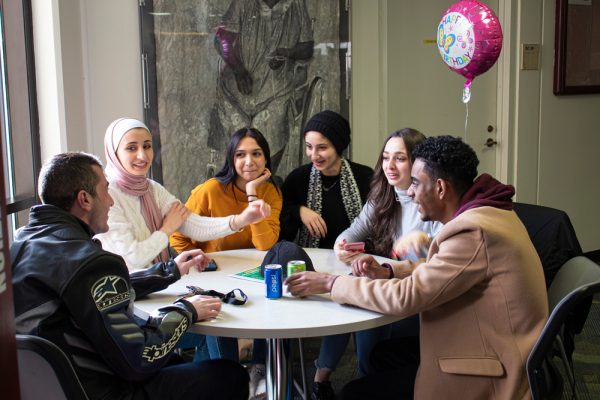 From left, WCC students Abrahim Alrawashdeh, Rawan Althabteh, Aya Alem, Saja Althabteh, Lillian Daghlas and Sami Adam talk and laugh on the second floor of the Student Center. The group of friends gathered to celebrate Alem’s 22nd birthday. Lilly Kujawski | Washtenaw Voice