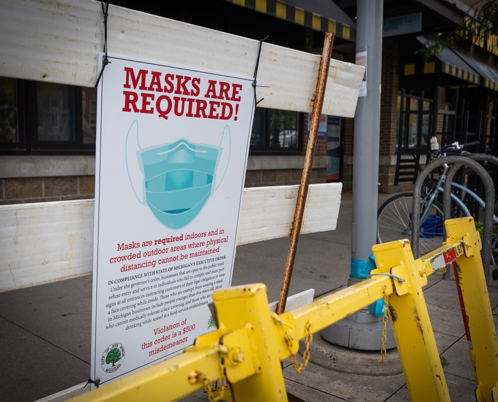 Sign on a blockade in Downtown Ann Arbor informing pedestrians about COVID-19 restrictions. Torrence Williams | Washtenaw Voice