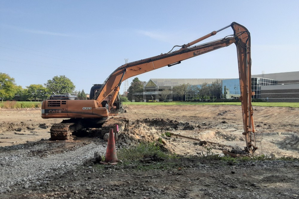 A piece of heavy machinery parked in front of what used to be the pond behind the Gunder Myran building. The pond has been drained for maintenance. Debra Destefani | Washtenaw Voice