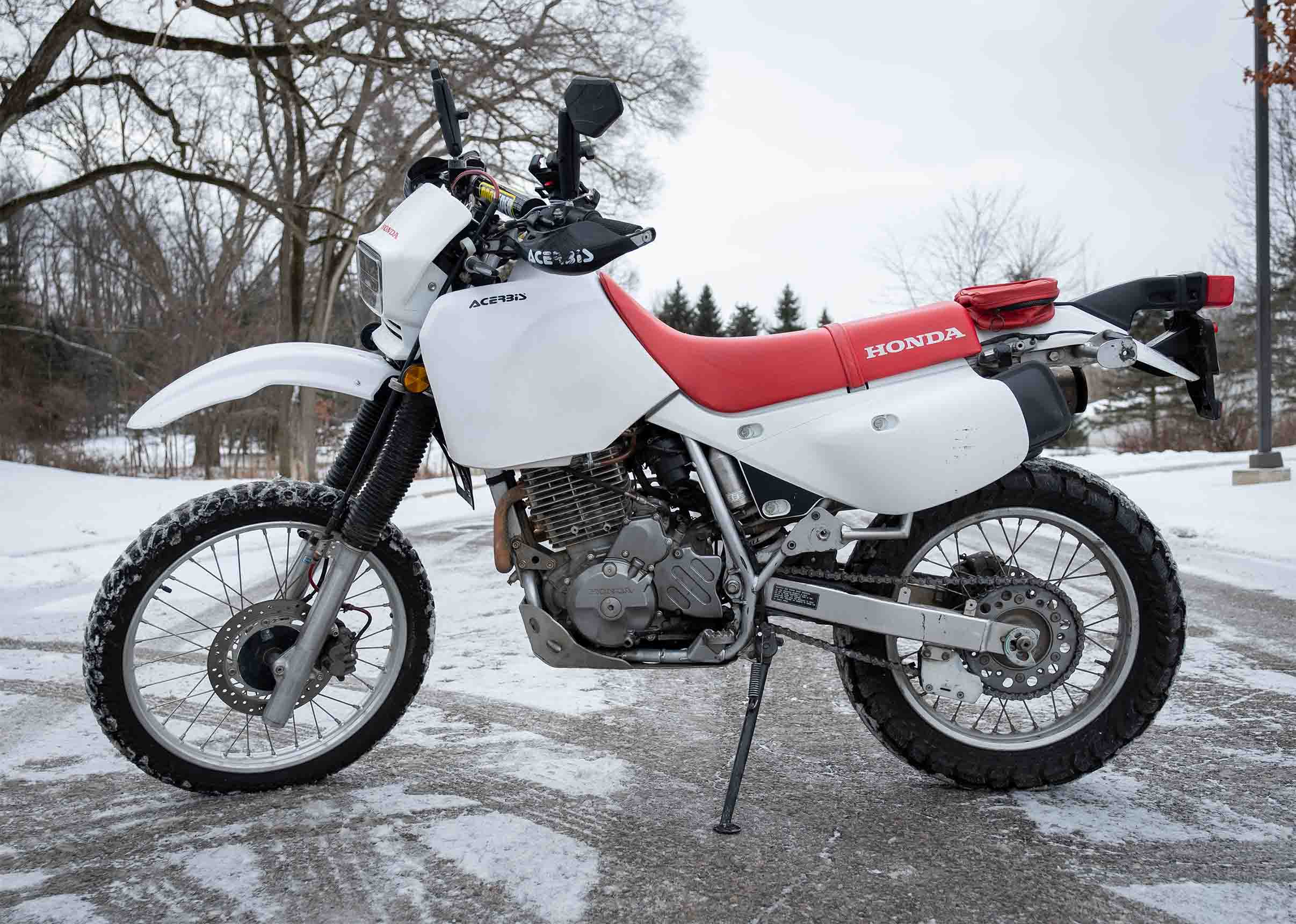 A red and white Honda motorcycle is posed on snow-covered pavement