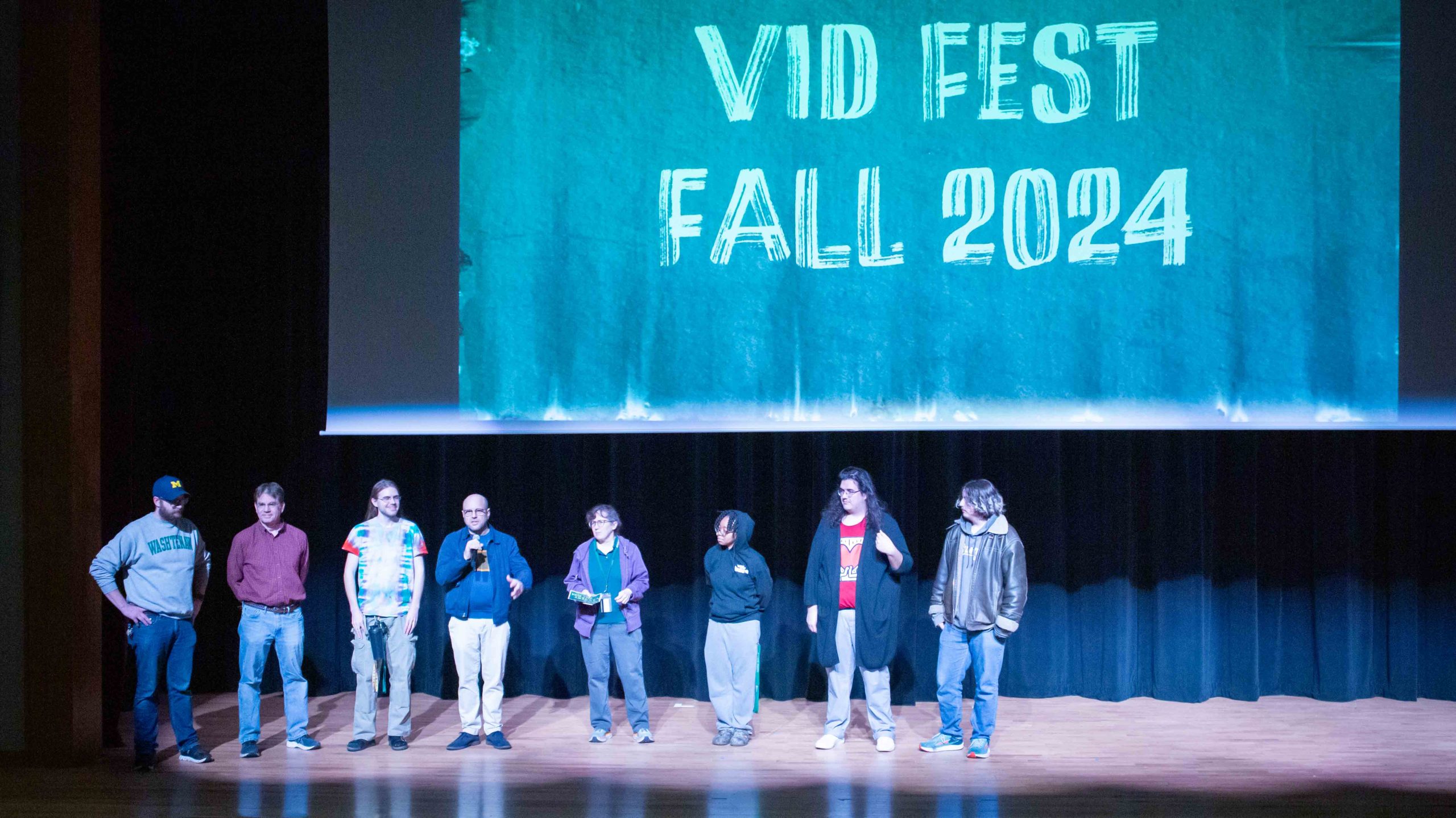 eight staff members stand on stage to introduce Vid Fest 2024