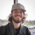 headshot of Stosh Zasadny from the shoulders up smiling and wearing a baseball cap