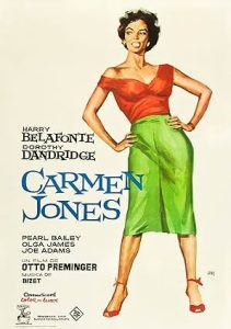 The poster for the film "Carmen Jones" shows a woman in an orange blouse and green pencil skirt with her hands on her hips.