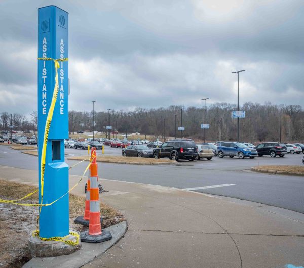 A blue phone assistance tower is shown under construction. Yellow caution tape and orange safety cones surround it.