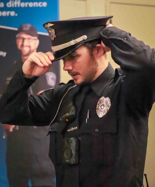 Police Officer Logan Lambertson adjusts his police cap. He is pictured in full uniform.