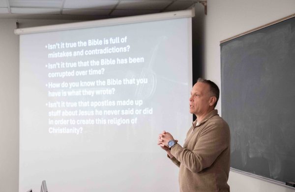Pastor Carey Waldie gives a lecture while standing in front of a projector screen.
