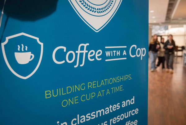A close-up of the standing banner for the event "Coffee with a Cop". It is light blue with white text.