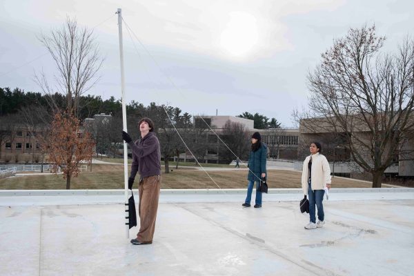 Jack Lozen holds a PVC pipe upright. Two other students hold sandbags with strings tied to the pipe to weigh it down.