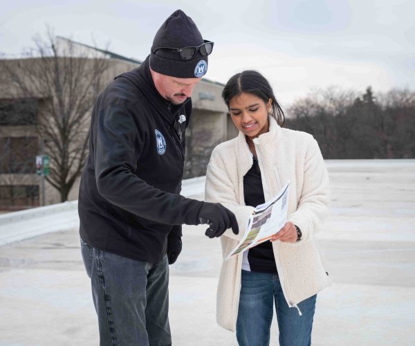 Sruthilaya Rajavelu-Mohan holds the instruction booklet while Alex Long points at the page. They both read the instructions.