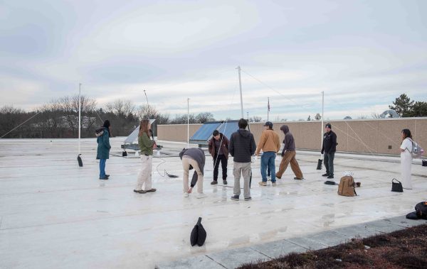 A view of the whole roof shows several students standing together. The four PVC pipes that make up the radio tower are shown.
