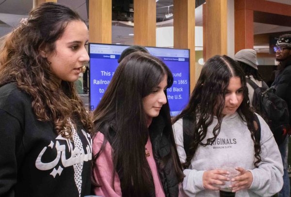 Three WTMC students stand closely together and listen to a Welcome Day volunteer.