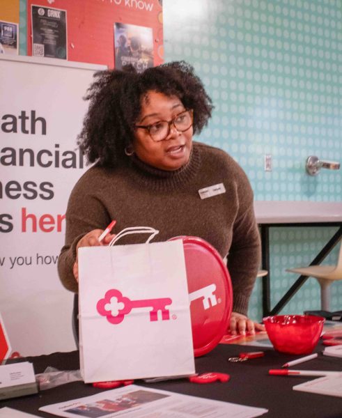 Takiyah Parker of Key Bank stands behind a table while holding Key Bank promotional materials.