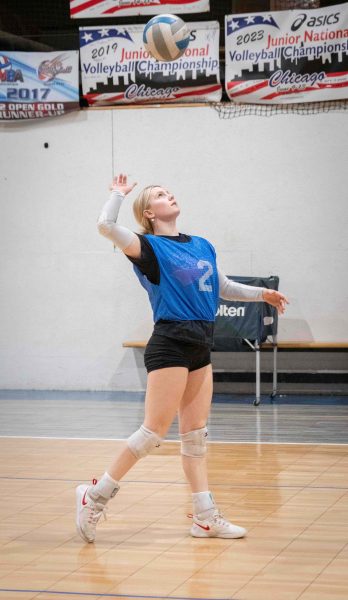 Mackenzie Roth looks upwards towards the volleyball above her head as she prepares to serve it.