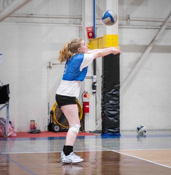 Julia Rem prepares to bump the volleyball, knees bent and arms out.