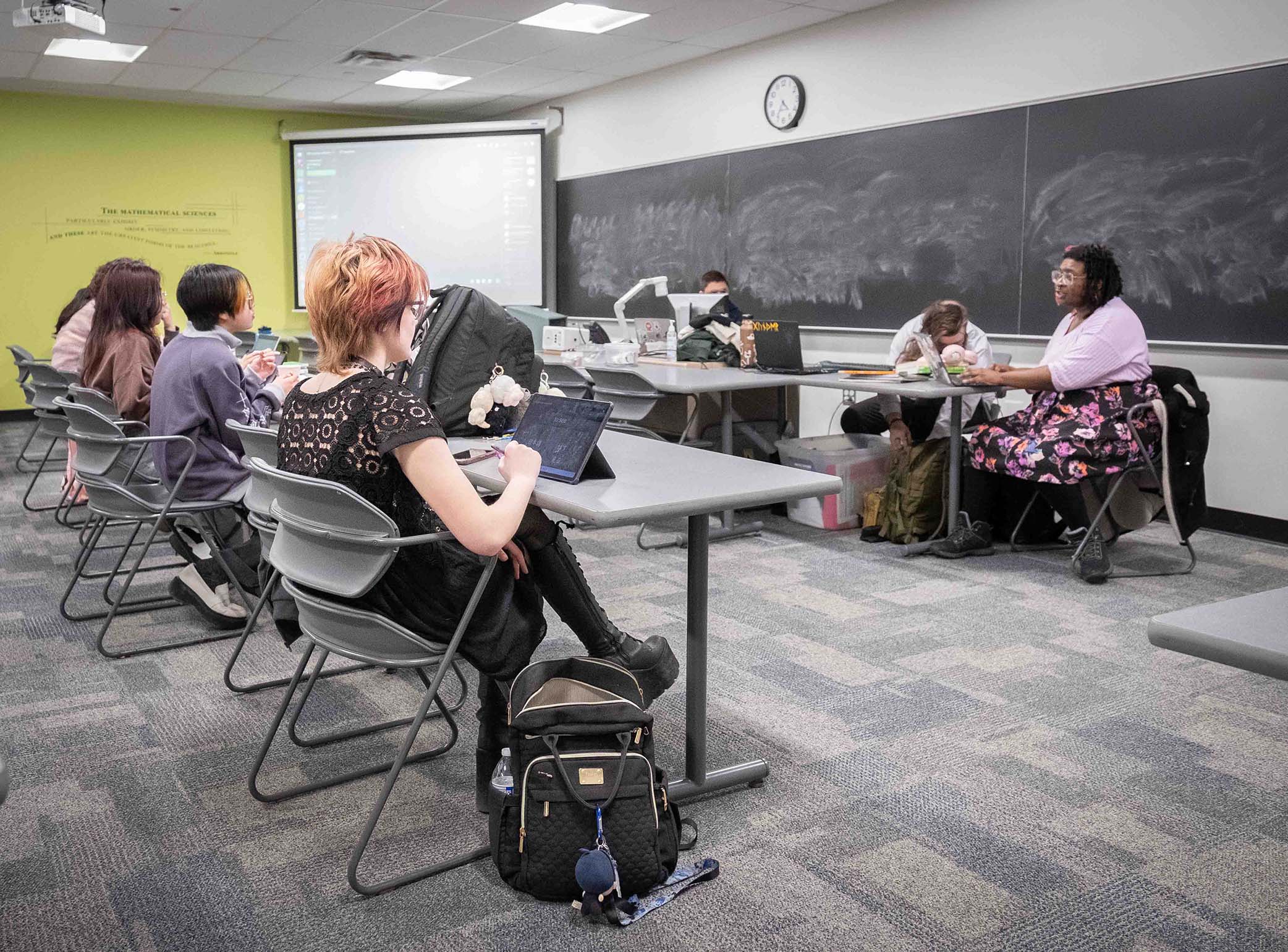 Wide-shot photo of the Japanese Culture Club meeting. The students sit at desks while they meet.