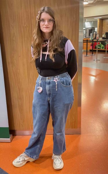 Moria Ferguson wears a pink and black hoodie, medium-wash jeans, and white tennis shoes.