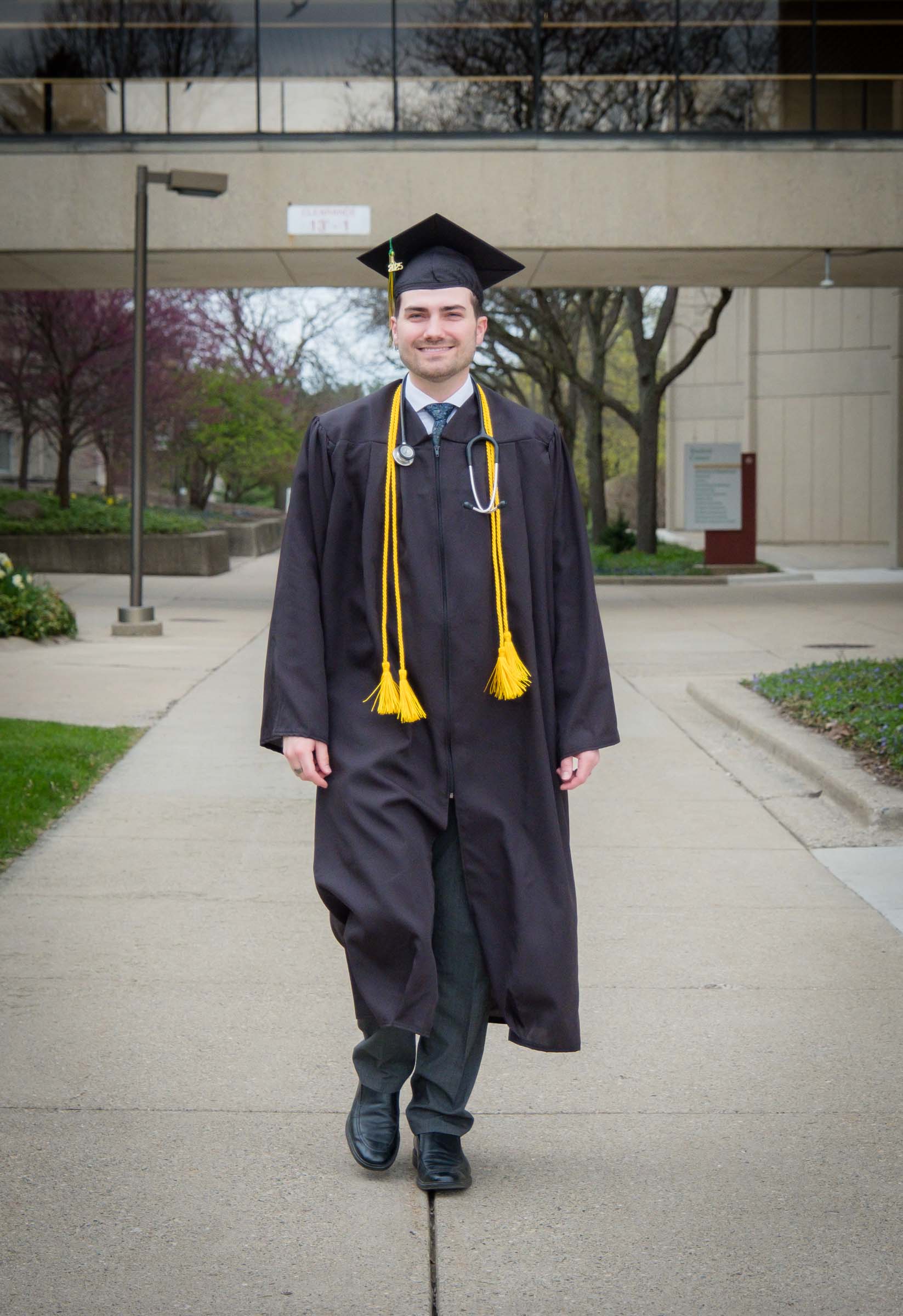 Bryan Wilson is shown on WCC campus walking towards the camera in his graduation robes.