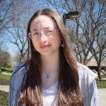 Headshot of Jillian Sullivan, smiling without teeth and wearing a gray zip hoodie.