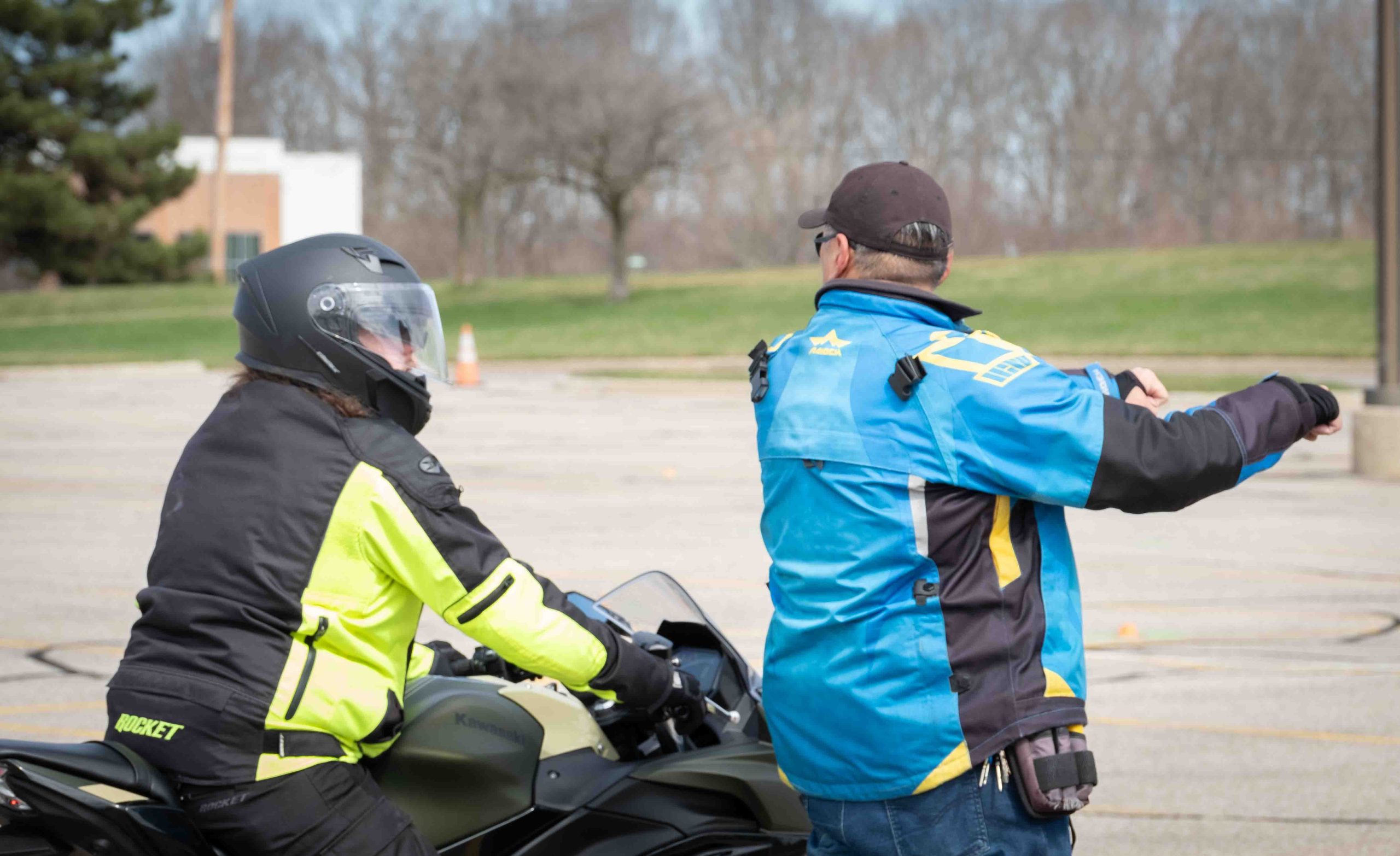 Christopher Fernandez and Uly Wong are shown with their backs to the camera. Fernandez sits on a bike while Wong stands.