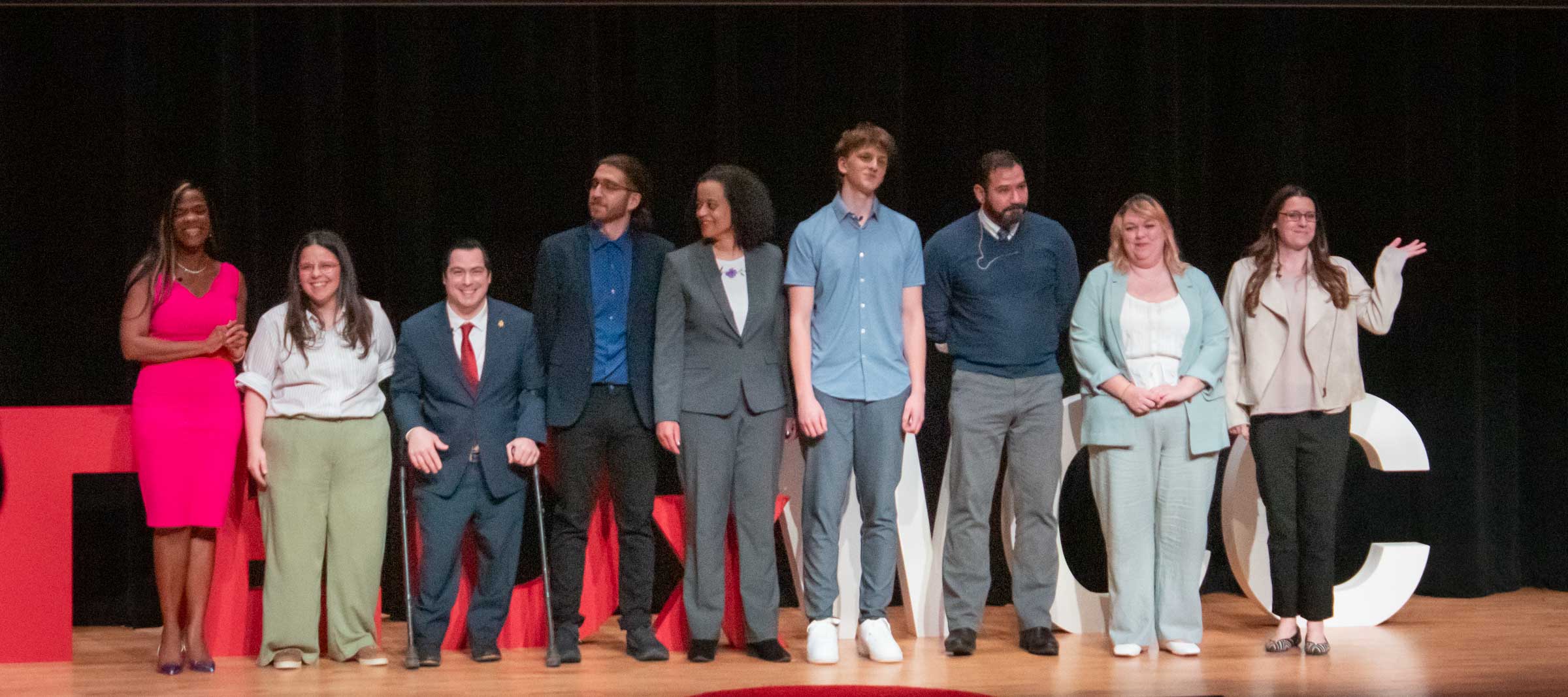 The nine participants pose for a group photo on the stage.
