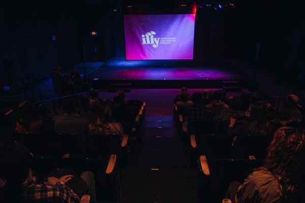 A dark theatre shows a screen with the words "iffy, Independent Film Festival Ypsilanti" projected in front of an audience.