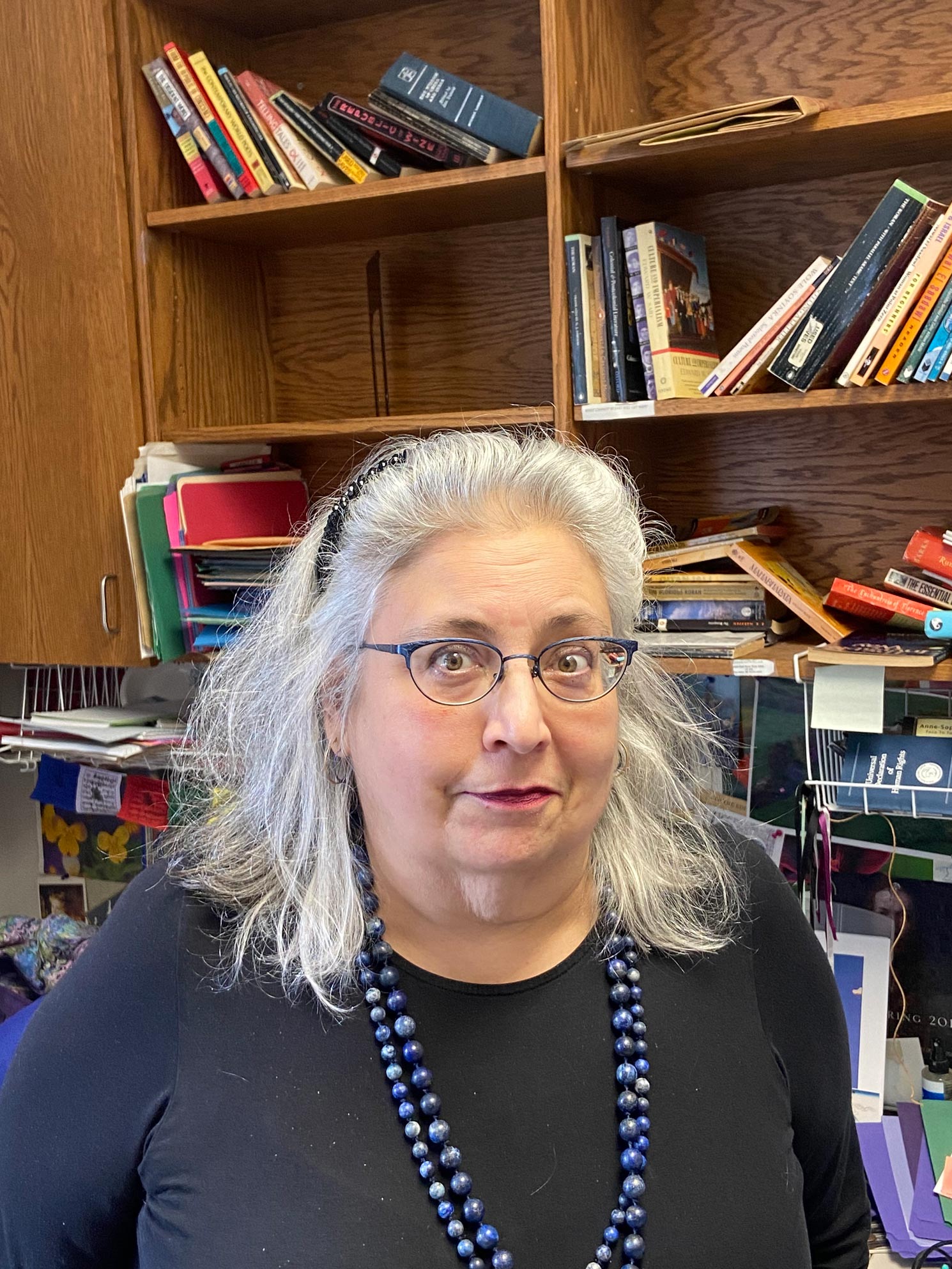 Headshot of Maryam Barrie smiling and wearing a blue shirt and beaded necklace.