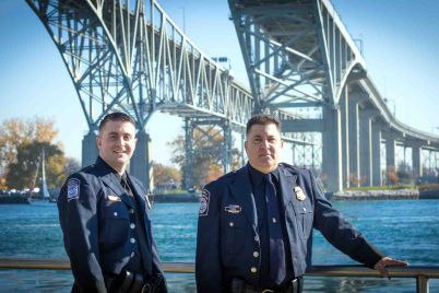 Andrew-Tower-left-and-his-father-Anthony-Cozza-stand-under-the-Blue-Water-Bridge-in-Port-Huron-in-November-2020-a-month-after-Cozzas-retirement-1.jpg